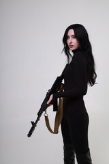 Beautiful slender brunette woman in black clothes with assault rifle