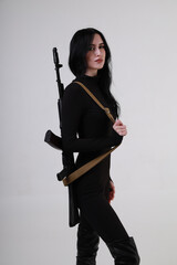Beautiful slender brunette woman in black clothes with assault rifle