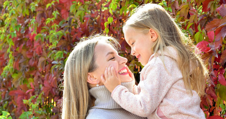 Mother and daughter on a walk. Autumn season. Bright autumn leaves. Sunny day. Happy family outdoors - 541461103