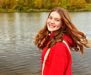 Young woman with long red hair outdoors in the fall. Beautiful young woman in autumn park. Autumn nature background - 541461130