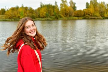 Young woman with long red hair outdoors in the fall. Beautiful young woman in autumn park. Autumn...