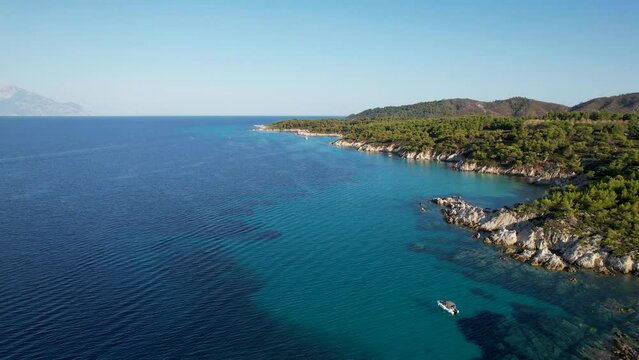 Aerial drone video of iconic turquoise and sapphire Paradise beach in Sithonia, Greece with the view on Atos mountain. Beautiful view of a sandy beach surrounded with high rocks