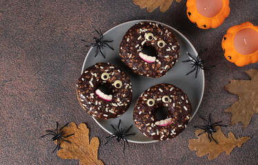 Halloween festive donuts with eyes and teeth on brown background, Top view