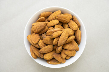 stack of almonds in a white bowl on gray background high quality closeup shot