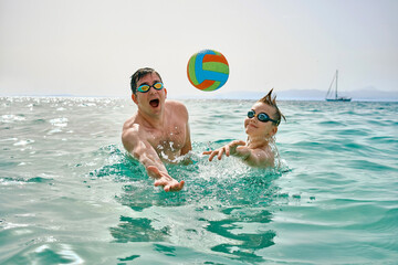 Happy family, father and son bonding, play ball, swim in the sea looking at view enjoying summer vacation. Togetherness Friendly concept
