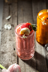 Strawberry and banana smoothie in tall glass on wooden background