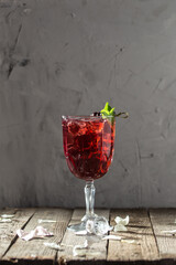 Berry alcoholic cocktail liqueur, vodka, ice and mint Refreshing drink on wooden table