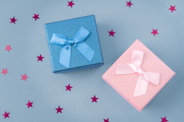 Pink and blue gift boxes with a bow on a blue background, confetti. Gift boxes