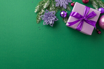 New Year concept. Top view photo of lilac giftbox with purple ribbon bow pink violet baubles snowflake flower ornaments pine branches in frost and sequins on isolated green background with copyspace
