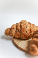 sweet healthy croissants decorated with sunflower seeds lie on a wooden kitchen round board on a white background.