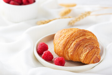 French breakfast fresh crispy croissant with raspberries.