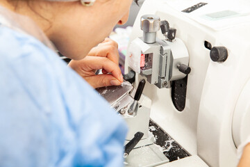 Closeup to the scientist hands working on a rotary microtome to obtain sections from a paraffin-embedded specimen.