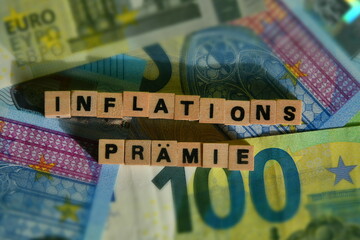Das Wort Inflationsprämie mit Holzbausteinen und Euroscheine