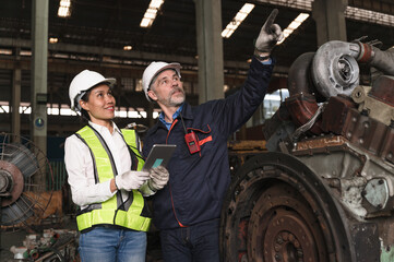 Two engineer man and woman use Tablet computer checking spares at factory spares train	