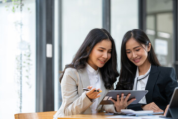 Fototapeta premium Asian female sales representatives in the section of Real estate talked and discussed tax plans to search for information Ask questions and give advice. All information is recorded and detailed.