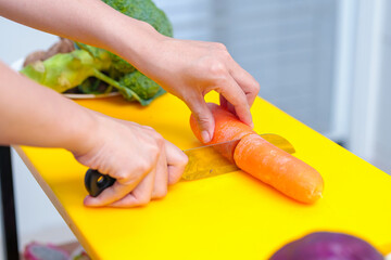 Obraz na płótnie Canvas Young woman cooking romantic dinner at home cutting vegetables close-up ,Closeup of human hands cooking vegetables salad in kitchen on the glass table with reflection