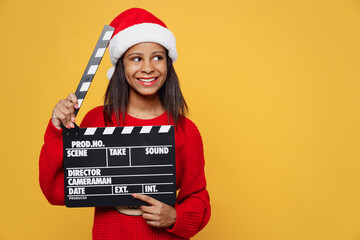 Merry little kid teen girl 13-14 year old in red xmas sweater Santa hat posing hold black film...