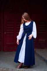 Fairytale princess wearing dress with medieval castle door on the background.