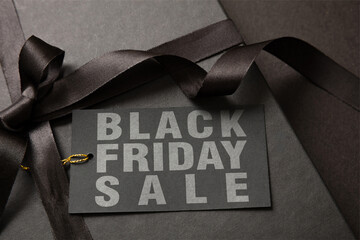Black Friday Sale text on a gift tag. Shopping box and ribbon, close up