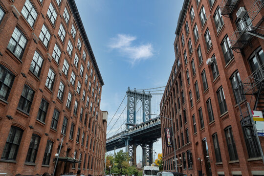Fototapeta Manhattan Bridge between Manhattan and Brooklyn over East River seen from a narrow alley enclosed by two brick buildings in in Dumbo, Brooklyn, new york city
