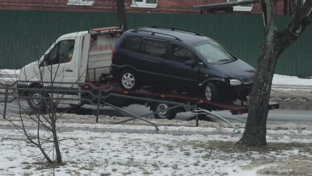 Evacuation of a broken car by a tow truck on a slippery road in winter. Snowing