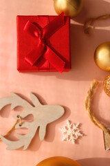 Small present, candy cane and various Christmas tree ornaments on pink background. Flat lay.