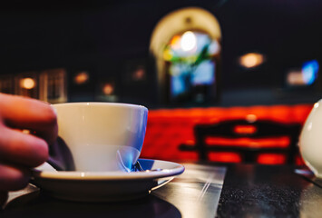 woman hand holding a white cup of tea or coffee standing on the table in cafe