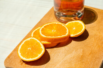 Oranges sliced on a wooden surface in the light of the sun.