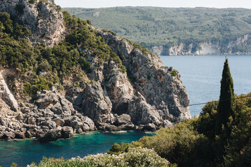 Corfu, Greece. Beautiful landscape with a view of huge mountains and gray rocks in blue water covered with green trees.