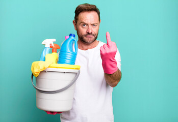 middle age man feeling angry, annoyed, rebellious and aggressive. housekeeper with clean products