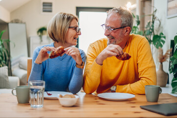 Senior couple eating breakfast at home and spending morning together