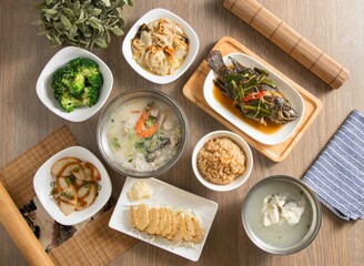 Assortment of Seafood congee, Braised sea tilapia, Gentian Grouper Soup, Shrimp Rice, Cabbage Braised, Zephyr Green Cauliflower, flower branch roll, Fish Ball Salad served dish top view of taiwan food