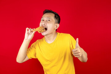 Portrait of asian young man with fried chicken in hand.
