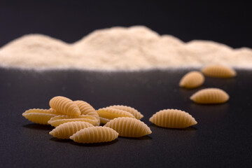 Fototapeta na wymiar Typical Sardinian pasta gnocchi with semolina flour on a black background