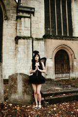 Fototapeta na wymiar Woman dress up as a sexy fallen angel in a cemetery, Halloween
