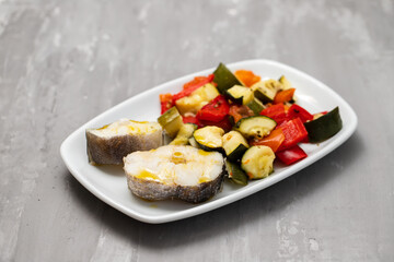 baked vegetables with boiled fish on white plate