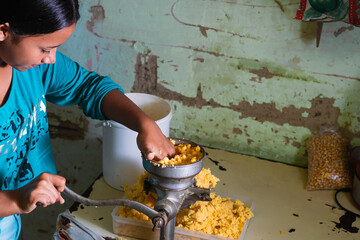 latina girl with brown skin, grinding the corn to prepare the traditional Colombian arepas. making the dough to make the arepas for breakfast.