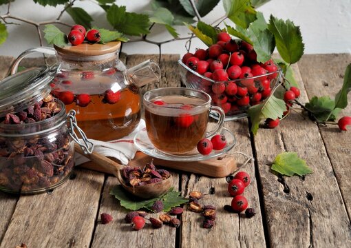 Tea with fresh and dried hawthorn berries in a glass cup on a wooden ancient background. Medicinal soothing herbal tea. Space for text.