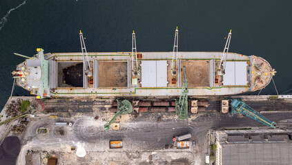 Loading dry cargo ship of brown sugar by cranes in port. Aerial view loading into holds of sea...