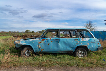 War in Ukraine. 2022 Russian invasion of Ukraine. Countryside. A destroyed civilian car stands on the side of the road. Holes from bullets and splinters on the body of the car - Powered by Adobe