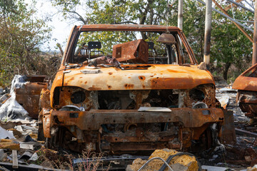 Fototapeta na wymiar War in Ukraine. 2022 Russian invasion of Ukraine. Countryside. A destroyed, burned-out civilian car stands in the courtyard of a destroyed house. No people. War crimes