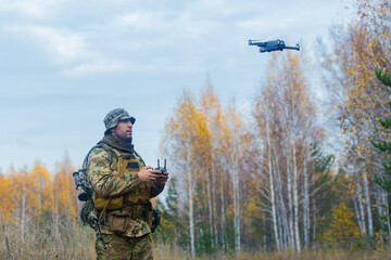 Mercenary soldier launch a reconnaissance drone in a forest. - obrazy, fototapety, plakaty