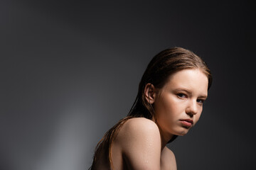 Fair haired model with wet shoulders looking at camera on grey background