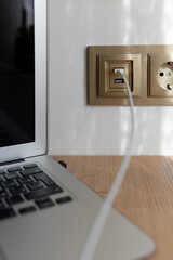 usb charging built into the wall with a wire. wired device charging via usb. charger cord close-up with a blurred background in the socket.