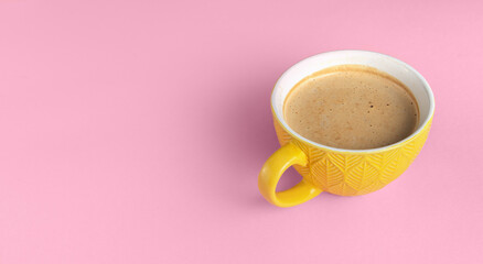 Yellow cup of coffee on a pink background front view. Banner with coffee and copy space for text.