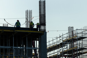 Builder workers working on construction site and sunset,beam, steel structure.Workers build large buildings on the construction site.Workers silhouette on contruction safty working.contruction concept