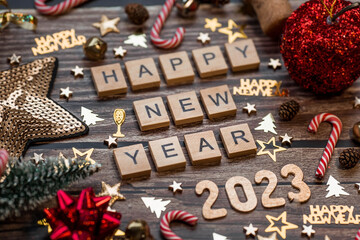 Banner. The symbol of the number 2023 with gold and red balls, stars, sequins and a Christmas tree on a wooden background. The concept of celebrating a Happy New Year 2023 and Christmas.
