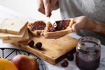 Crop man preparing toasts with cherry jam