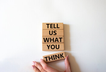 Tell us what you think symbol. Wooden blocks with words Tell us what you think. Beautiful white background. Businessman hand. Business and Tell us what you think concept. Copy space.