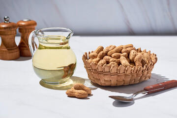 Peanut oil in a glass jug and raw peeled groundnut. Alternative and healthy food option.